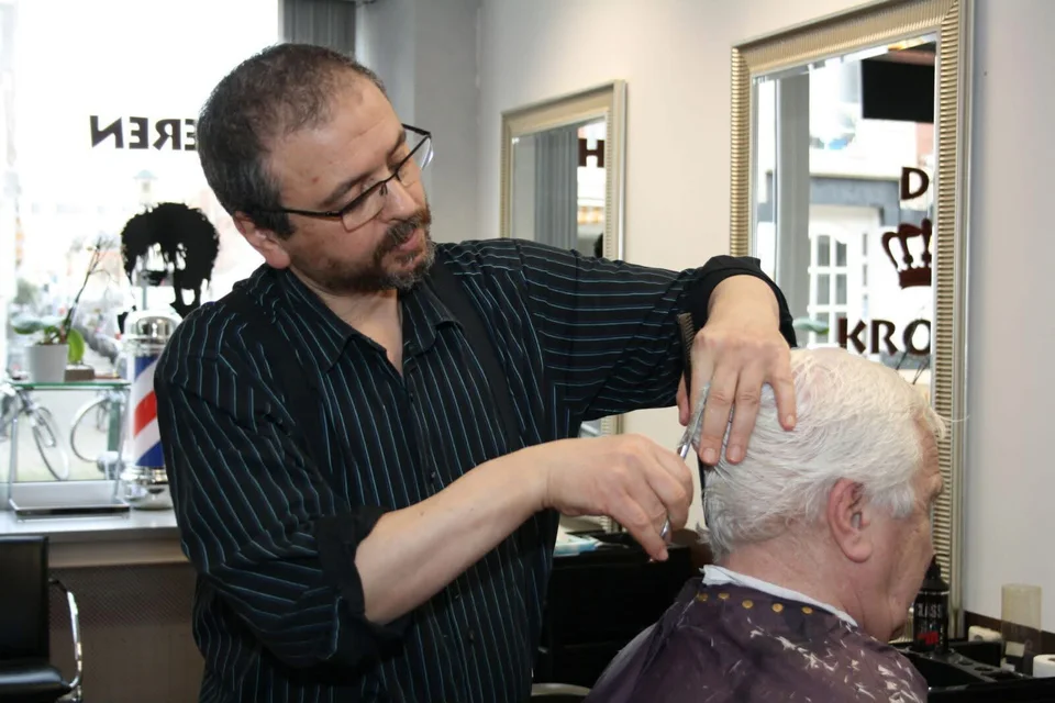 Salah knipt het haar van een klant bij Kapsalon De Kroon